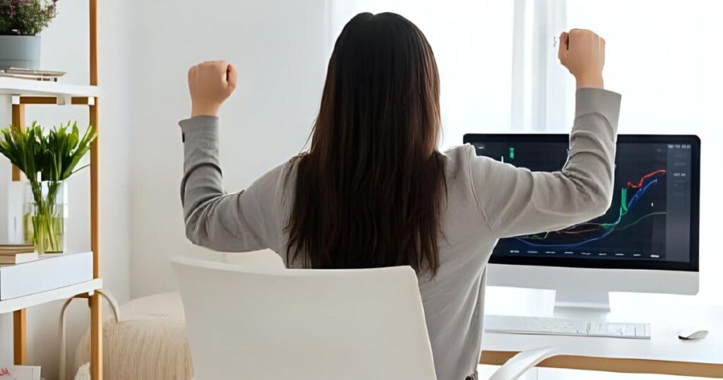 パソコンの画面の前で喜んでいる女性